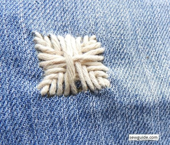repairing and fixing holes on jeans with decorative stitch which is handmade
