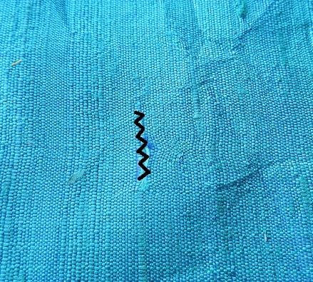 mending fabric holes by making zig zag stitches across the hole